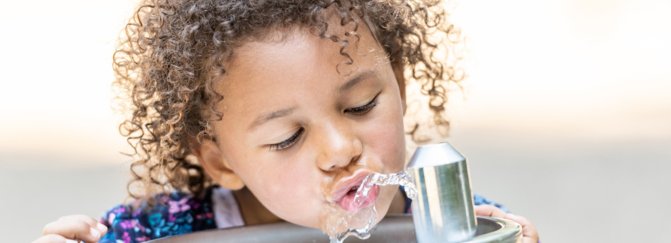 Child outdoors drinking from water fountain